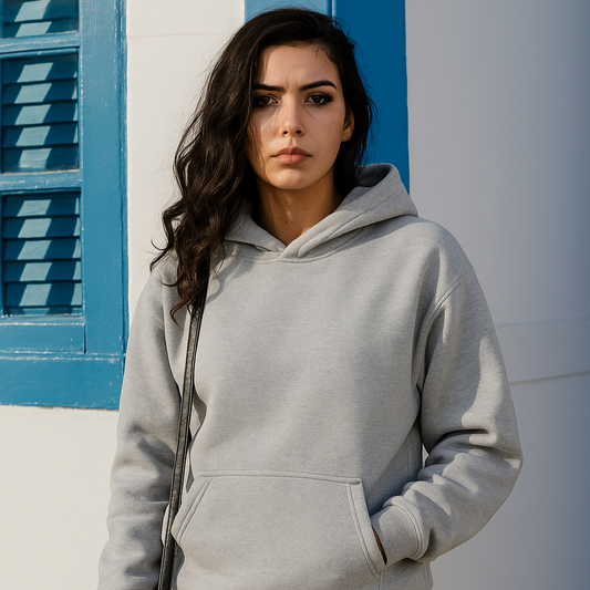 Woman wearing a gray hoodie standing against a blue and white wall.